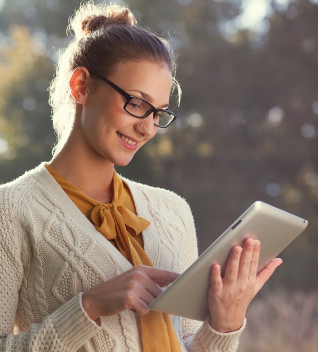 happy woman in glasses using tablet pc in the park